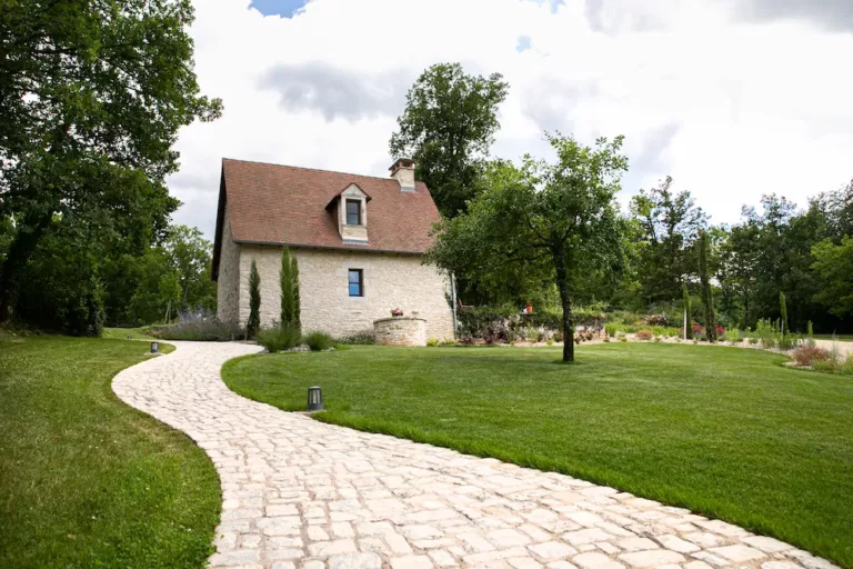 Allée entouré de gazon et espaces arborés menant à une maisonnette.