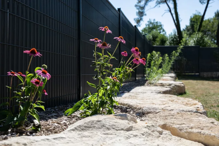 Jolie clôture au pied duquel se trouve un habillage fleuri entouré de pierres périgourdines.